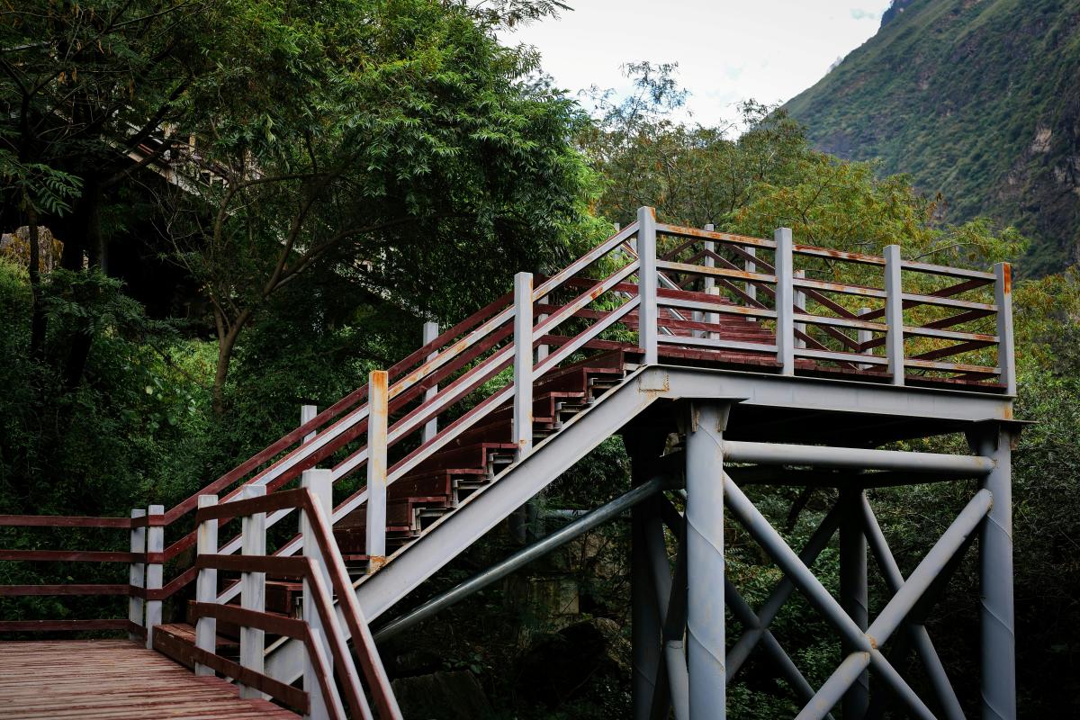 Rusted staircase surrounded by foliage and mountains
